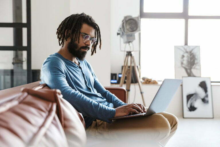 Handsome young african man sitting on a leather couch at home